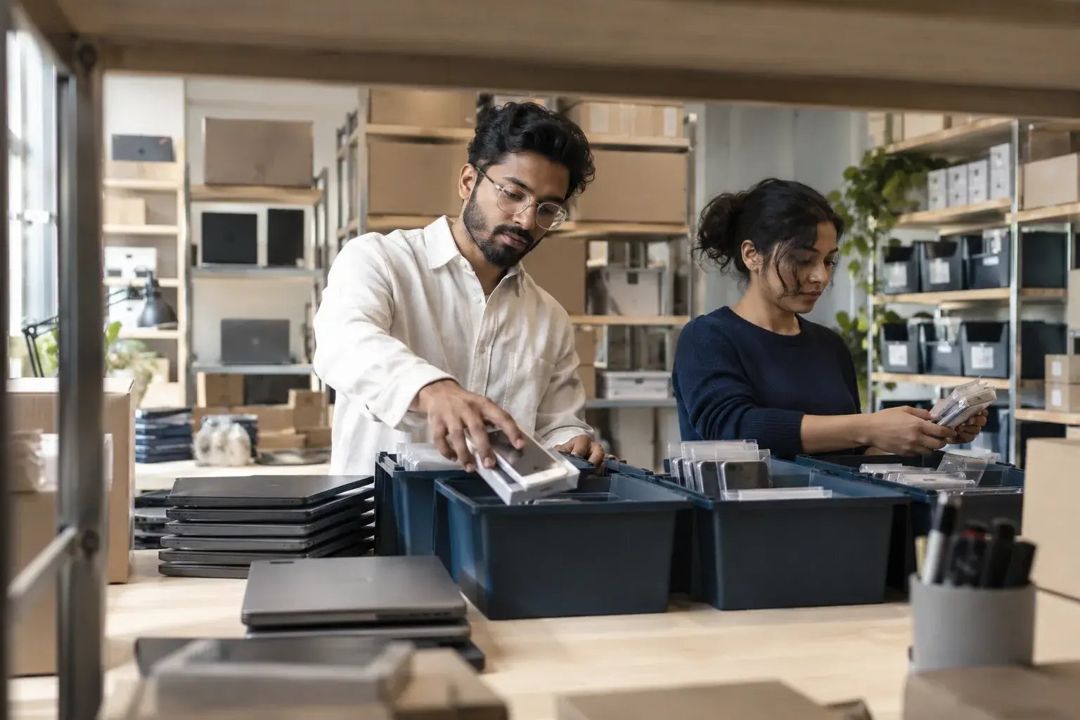 Un entrepreneur organisant un lot de commandes avec un collègue. Produits : téléphones et ordinateurs portables remis à neuf.