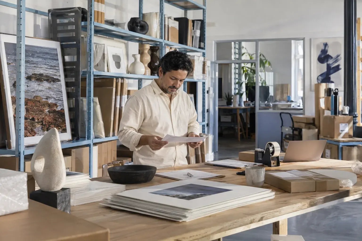Un professionnel préparant les documents d’une commande internationale. Produits : estampes et objets de design.