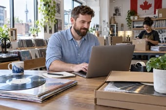 Shop owner reviewing online store orders on a laptop in a retail studio