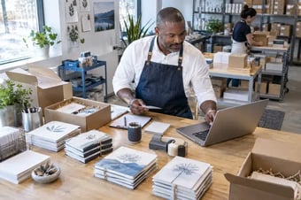 Responsable des opérations regroupant les commandes selon les emballages et services d’expédition habituels, à un poste avec ordinateur portable