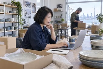Shop owner reviewing online store orders on a laptop in a retail studio