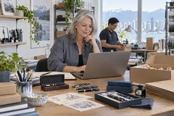 Shop owner reviewing online store orders on a laptop in a retail studio