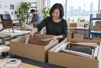 Commerçant répartissant les composants d’un même produit volumineux dans deux boîtes d’expédition distinctes