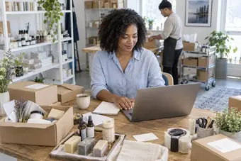 Shop owner reviewing online store orders on a laptop in a retail studio