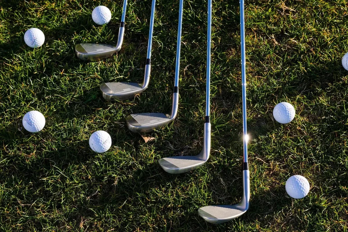 Golf clubs and balls arranged on grass for a sporting goods assortment